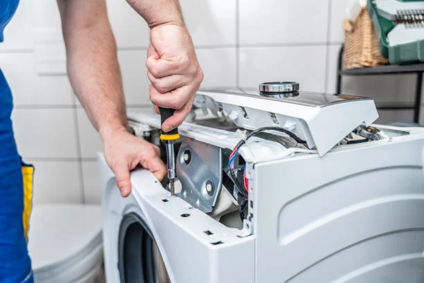Close-up of a technician using a screwdriver on an appliance control assembly