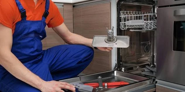 Technician holding a removed dishwasher component during service